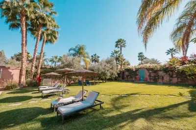 a group of lounge chairs and umbrellas on a lawn at Villa Magtafa in Marrakech