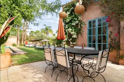 a table with chairs and an umbrella in a yard at Villa Magtafa in Marrakech