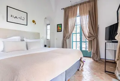 a bedroom with a large white bed and a television at Villa Magtafa in Marrakech