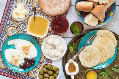 a table topped with plates of eggs and bread at Sultan Luxury Camp in Merzouga