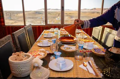 a person is setting a table in a restaurant at Luxury Desert Queen Camp in Merzouga