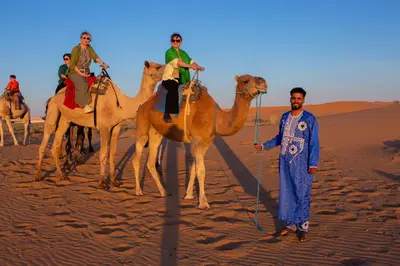 a group of people riding on camels in the desert at Luxury Desert Queen Camp in Merzouga