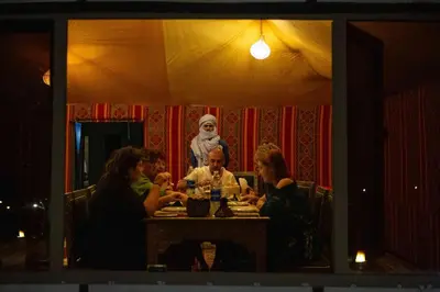 a group of people sitting at a table in a restaurant at Luxury Desert Queen Camp in Merzouga