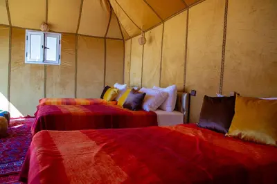 a room with two beds and a couch in a tent at Luxury Desert Queen Camp in Merzouga