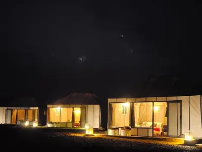 a couple of buildings at night with lights at Luxury Desert Queen Camp in Merzouga