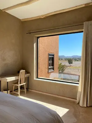 a bedroom with a large window and a desk at Kasbah Tamsna in Ouarzazate