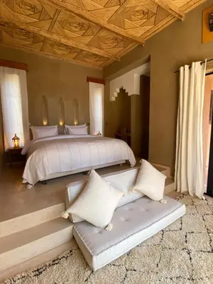 a bedroom with a large bed with white sheets and pillows at Kasbah Tamsna in Ouarzazate