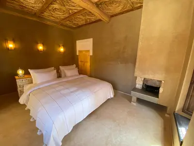 a bedroom with a white bed and a fireplace at Kasbah Tamsna in Ouarzazate