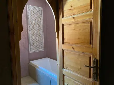 a bathroom with a tub and a toilet and a door at Kasbah Tamsna in Ouarzazate