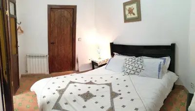 a bedroom with a bed with a quilt on it at Dar Ines in Moulay Idriss Zerhoun
