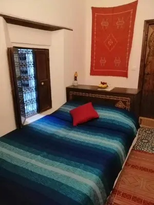a bedroom with a bed with a red pillow on it at Dar Ines in Moulay Idriss Zerhoun