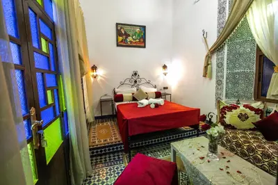 a bedroom with a bed with a red blanket and a window at DAR EL AAMOURI in Fès