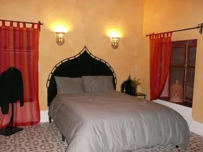 a bedroom with a large bed with red curtains at kasbah 123 soleil in Skoura