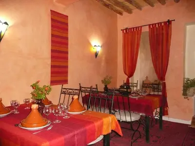 a dining room with two tables with red tablecloths at kasbah 123 soleil in Skoura