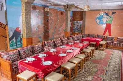 a dining room with red tables and chairs and a mural at Hotel Awayou in Bou Tharar