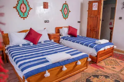 two beds sitting in a room with at Hotel Awayou in Bou Tharar