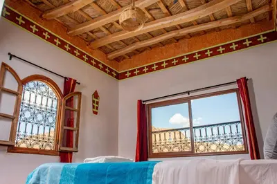 a bedroom with a window and a balcony at Hotel Awayou in Bou Tharar