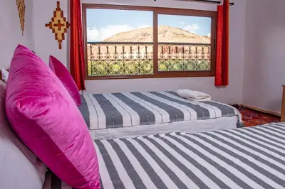 two beds in a room with a window at Hotel Awayou in Bou Tharar
