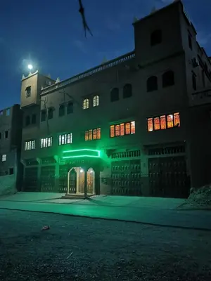a large building with green lights on it at night at Hotel Awayou in Bou Tharar