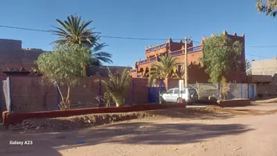 a street with a fence and palm trees and a building at Maroc Galacx in Ouarzazate