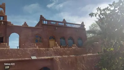 a brick house with blue windows on top of a wall at Maroc Galacx in Ouarzazate