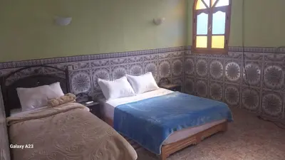 a bedroom with two beds and a window at Maroc Galacx in Ouarzazate