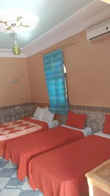 two beds in a room with red sheets at Maroc Galacx in Ouarzazate