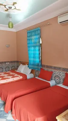 two beds in a room with red and blue sheets at Maroc Galacx in Ouarzazate