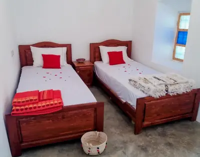 two beds in a bedroom with red pillows on them at ZEN ECOLODGE in Tighli