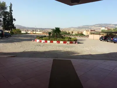 a parking lot with some plants and cars parked at HOTEL CONTINENTAL Khénifra in Khenifra