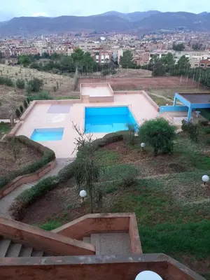 a swimming pool on a hill with a city in the background at HOTEL CONTINENTAL Khénifra in Khenifra