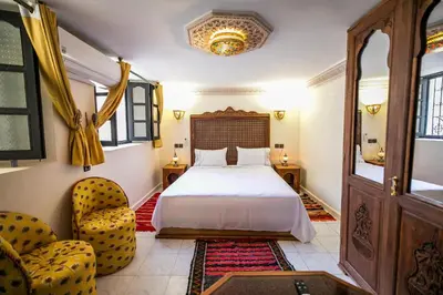 a bedroom with a bed and two chairs at Dar Layali Fez in Fès