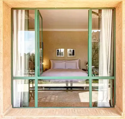 a bedroom with a bed through a glass window at Jenan Mayshad Marrakech, Luxurious Private Domaine with Pool and Padel Court in Marrakech