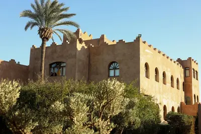 an old building with a palm tree in front of it at Jenan Mayshad Marrakech, Luxurious Private Domaine with Pool and Padel Court in Marrakech