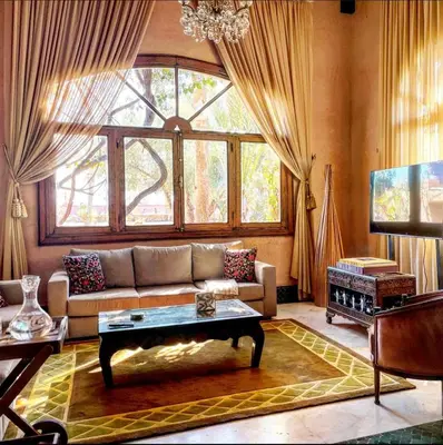 a living room with a couch and a large window at Jenan Mayshad Marrakech, Luxurious Private Domaine with Pool and Padel Court in Marrakech