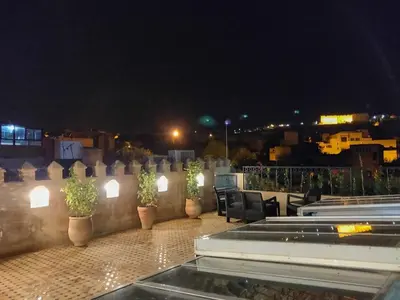 a rooftop patio at night with chairs and plants at Riad Sidrat Fes in Fès