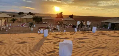 a group of tents in the desert at sunset at Nomads Dunes Nest in Merzouga