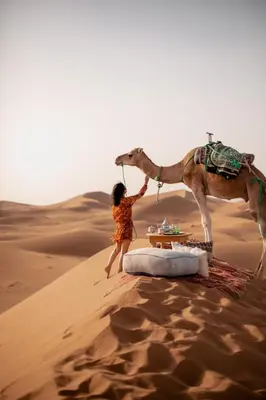 a young girl standing next to a camel in the desert at Nomads Dunes Nest in Merzouga
