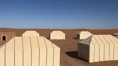 a group of white structures in the desert at Riad Assia Foum Zguid in Foum Zguid