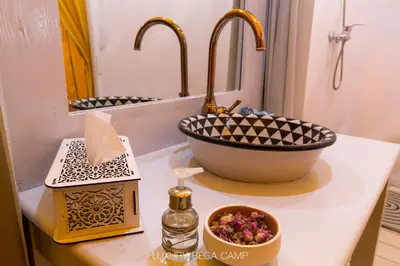 a bathroom counter with a sink and a bowl of flowers at Luxury Bega Camp in Merzouga