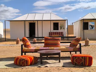 a couch and ottoman in front of a building at Luxury Bega Camp in Merzouga