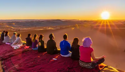 a group of people sitting on top of a mountain watching the sunset at Luxury Bega Camp in Merzouga