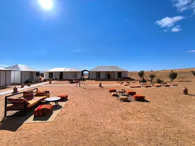 a group of benches and tables in the desert at Luxury Bega Camp in Merzouga