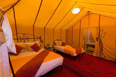 a bedroom with two beds in a tent at Luxury Bega Camp in Merzouga