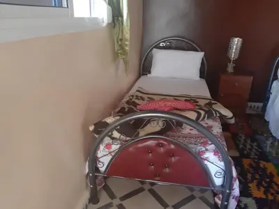 a small bedroom with a bed in a corner at Guests House in Merzouga