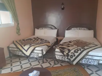 two twin beds in a room with a tiled floor at Guests House in Merzouga