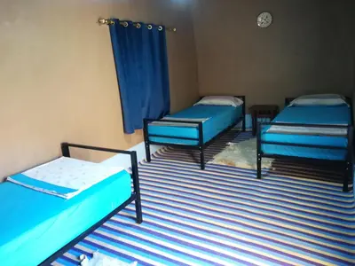 a room with three beds and a blue curtain at Gite Amoudou in Ouarzazate