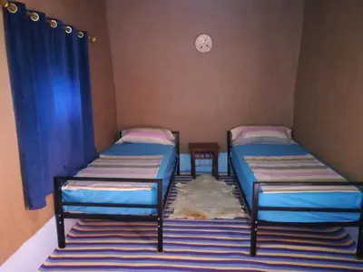 a room with two beds and a clock on the wall at Gite Amoudou in Ouarzazate