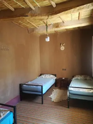 two beds sitting in a room with a rug at Gite Amoudou in Ouarzazate