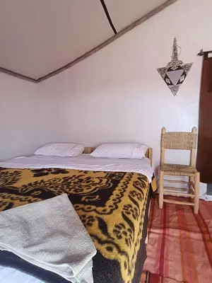 a bedroom with two beds and a chair in it at Camp Ayour Mhamid in Mhamid
